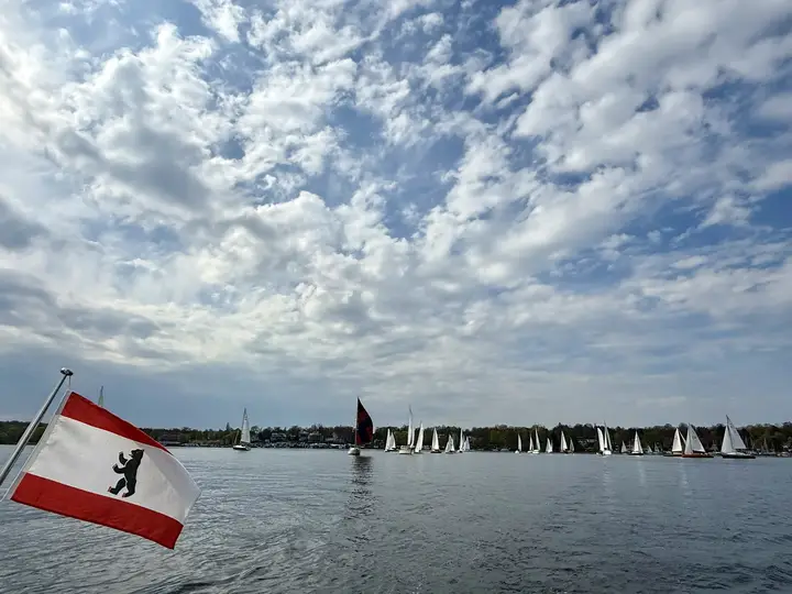 Berliner Flagge am Heck, im Hintergrund ein Regattafeld auf dem Wannsee