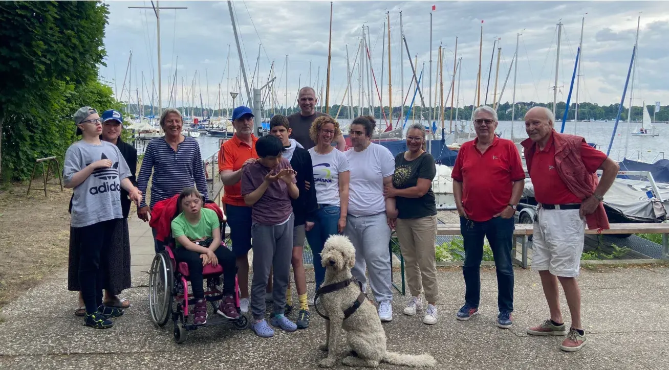 Gruppenfoto am Hafen der BSV: Schülerinnen und Schüler, teils im Rollstuhl, mit Betreuerinnen, Betreuern, Skippern und einem Hund vor den Segelbooten