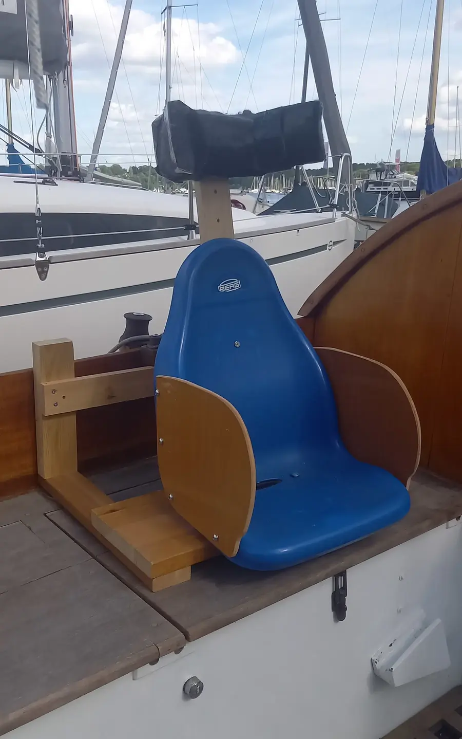 Ein blauer Kettcar-Sitz ist an Deck eines Segelboots festgeschraubt und dient als gesicherter Sitzplatz